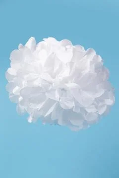 White flower made of thin white paper on a blue background. Stock Photos