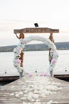 White flowers cascade around a rustic wooden arch Stockfoto's
