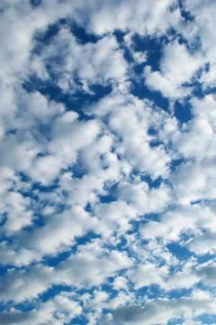 White, fluffy altocumulus clouds on a clean, blue summer sky. Stock Photos