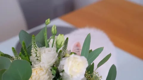 White fluffy cat sniffing bouquet of roses indoors on white surface Video stock 342018024
