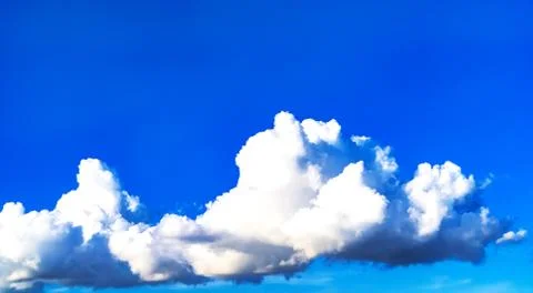 White fluffy clouds against a clear blue sky. Stock Photos