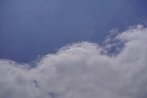 White fluffy clouds against a clear blue sky background Stock Photos