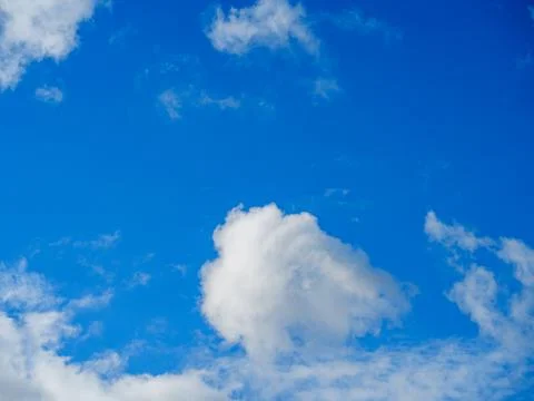 White fluffy clouds against the light blue sky Stock Photos