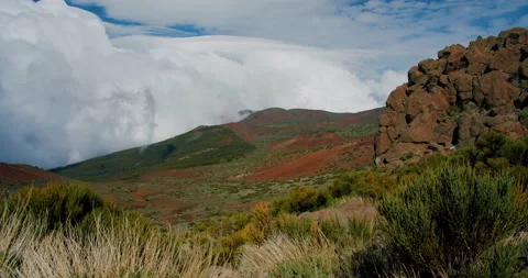 White fluffy clouds are below the forest peak of the mountain. Wind weather at Stock Footage 200601546