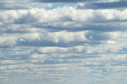 White fluffy clouds on a background of blue sky in summer. The concept of wea Stock Photos