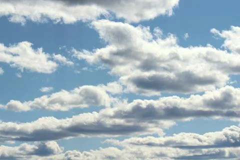 White fluffy clouds on a background of blue sky in summer. The concept of wea Stock Photos