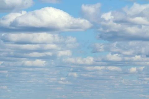 White fluffy clouds on a background of blue sky in summer. The concept of wea Stock Photos