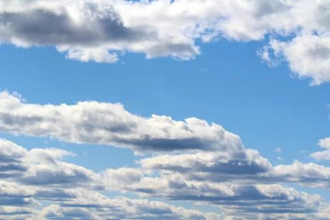 White fluffy clouds on a background of blue sky in summer. The concept of wea Stock Photos