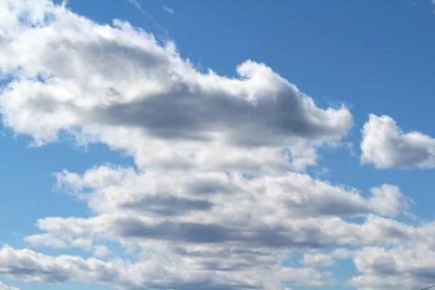 White fluffy clouds on a background of blue sky in summer. The concept of wea Stock Photos