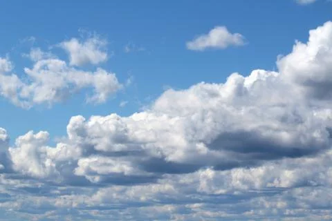 White fluffy clouds on a background of blue sky in summer. The concept of wea Stock Photos