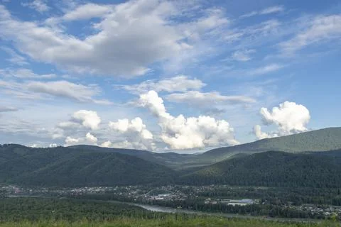 White fluffy clouds on blue sky and mountain peaks Stock-Fotos