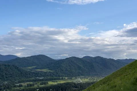 White fluffy clouds on blue sky and mountain peaks Stock Photos