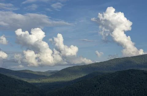 White fluffy clouds on blue sky and mountain peaks Stock Photos