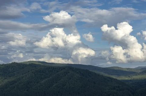 White fluffy clouds on blue sky and mountain peaks Stock Photos