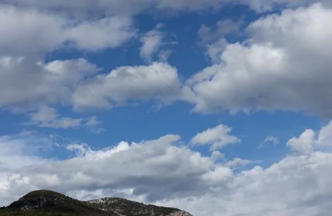 White fluffy clouds in the blue sky over the mountain Stock Photos