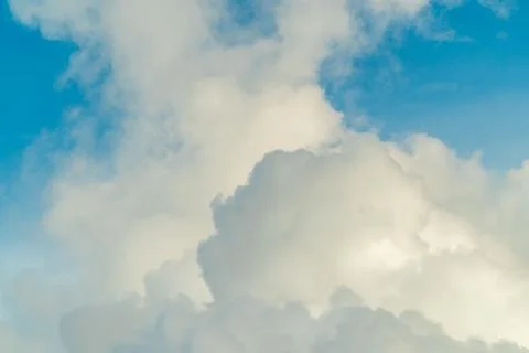 White fluffy clouds in a blue sky. Natural background and texture. Stock Photos