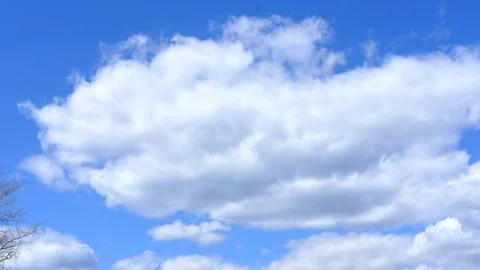 White fluffy clouds in blue sky with soft sunlight illuminating the clouds and Stock Photos