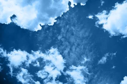 White fluffy clouds in a bright blue sky on a sunny day. Stock Photos