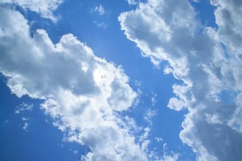 White fluffy clouds in a bright blue sky on a sunny day. Stock Photos