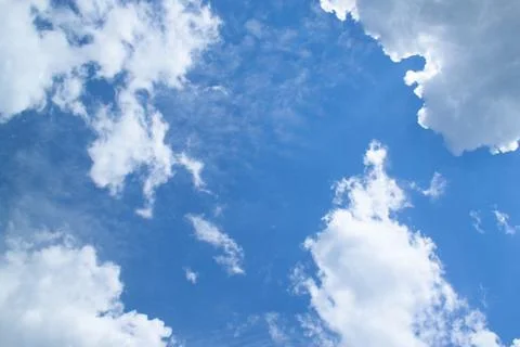 White fluffy clouds in a bright blue sky on a sunny day. Stock Photos