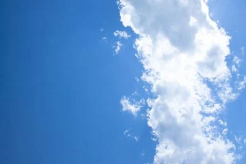 White fluffy clouds in a bright blue sky on a sunny day. Stock Photos