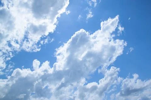 White fluffy clouds in a bright blue sky on a sunny day. Stock Photos