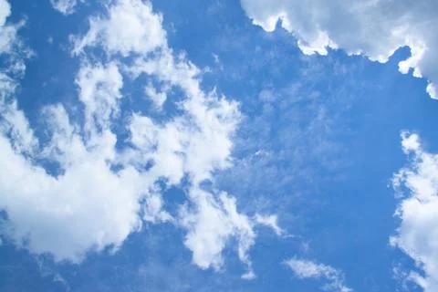 White fluffy clouds in a bright blue sky on a sunny day. Stock Photos