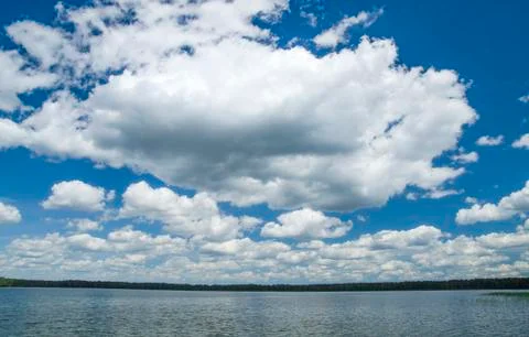 White fluffy clouds in the deep blue summer sky Stock Photos
