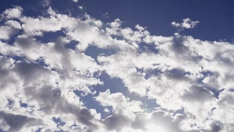 White fluffy clouds drifting across a clear blue sky Stock Footage 329751175