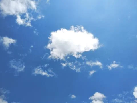 White fluffy clouds drifting in a bright clear blue sky with atmosphere daylight Stock-Fotos