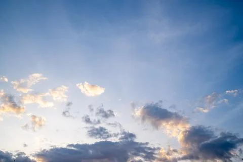 White fluffy clouds float gently in a clear blue sky on a bright sunny day... Stock Photos