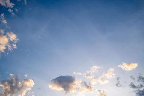 White fluffy clouds float gently in a clear blue sky on a bright sunny day... Stock Photos