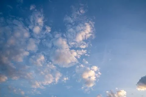 White fluffy clouds float gently in a clear blue sky on a bright sunny day... Stock Photos