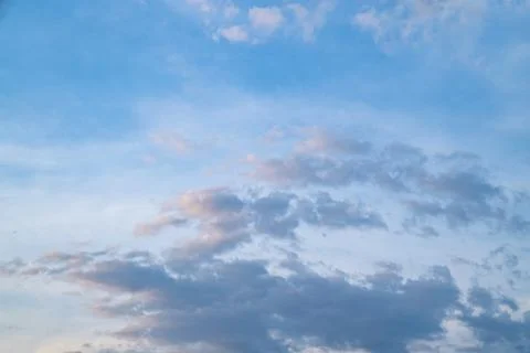 White fluffy clouds float gently in a clear blue sky on a bright sunny day... Stock Photos