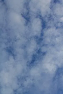 White fluffy clouds floating across the deep blue sky on a bright sunny day. Stock Photos