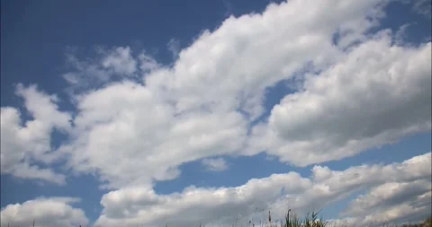 White fluffy clouds floating in the blue sky in a time-lapse video Stock Footage 275350963