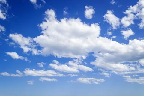 White fluffy clouds high in a bright blue sky on a sunny spring day. Stock Photos