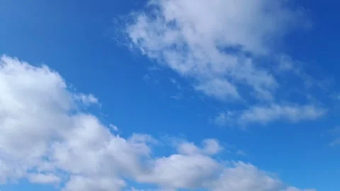 White fluffy clouds moving across a bright blue sky in real time Stock Footage 330160906