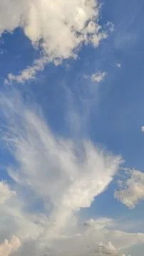 White fluffy clouds moving across a clear blue sky Stock Photos