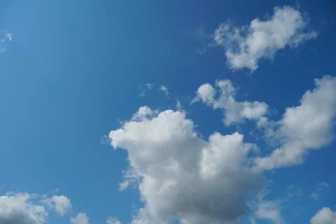White fluffy clouds in the sky. Blue sky and cloud cover on a sunny summer da Stock Photos