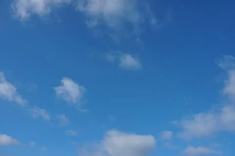White fluffy clouds in the sky. Blue sky and cloud cover on a sunny summer da Stock Photos