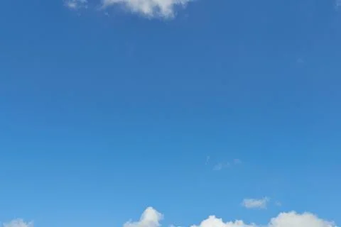 White fluffy clouds in the sky. Blue sky and cloud cover on a sunny summer da Stock Photos