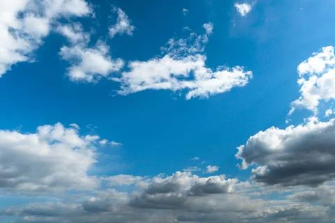 White fluffy clouds in the sky. Blue sky and cloud cover on a sunny summer da Stock Photos