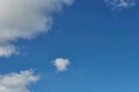 White fluffy clouds in the sky. Blue sky and cloud cover on a sunny summer da Stock Photos