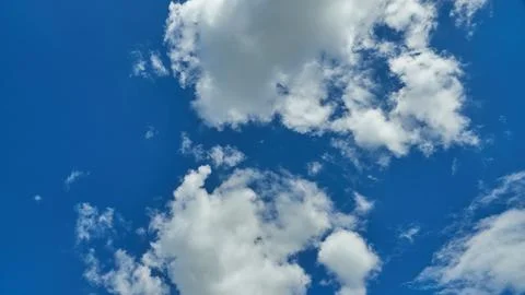 White fluffy clouds in the sky. Blue sky and cloud cover on a sunny summer da Stock Photos