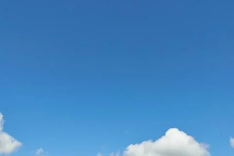 White fluffy clouds in the sky. Blue sky and cloud cover on a sunny summer da Stock Photos