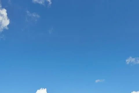 White fluffy clouds in the sky. Blue sky and cloud cover on a sunny summer da Stock Photos