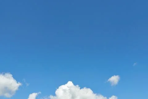 White fluffy clouds in the sky. Blue sky and cloud cover on a sunny summer da Stock Photos