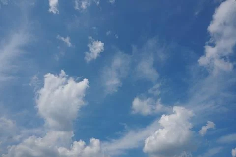 White fluffy clouds in the sky. Blue sky and cloud cover on a sunny summer da Stock Photos