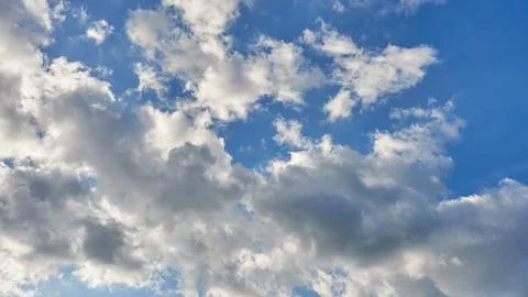 White fluffy clouds in the sky. Blue sky and cloud cover on a sunny summer da Stock Photos